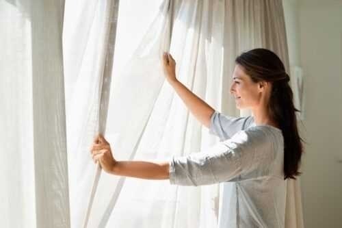 Женщина открывает шторы